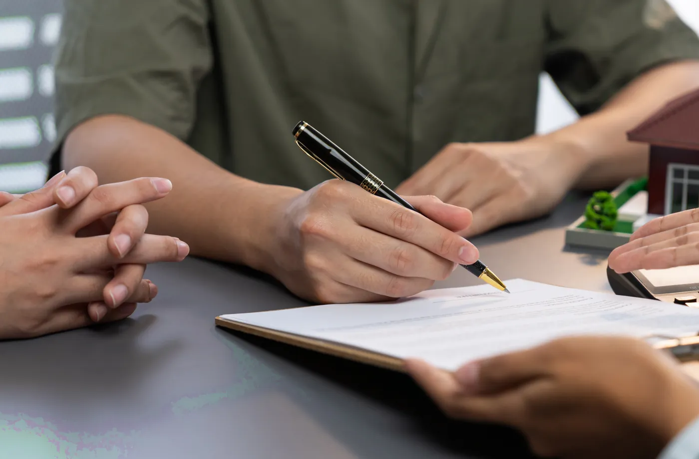 Twee mensen ondertekenen een akte aan tafel, met een vulpen boven het document